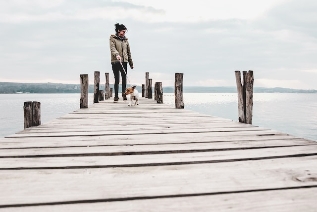 Eine Frau mit Ihrem Hund auf einem Steg am See